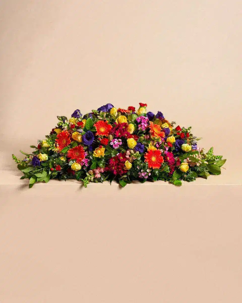 Livraison Gerbe de fleur : Arrangement de fleurs colorées repose sur une surface beige dans un cadre épuré.