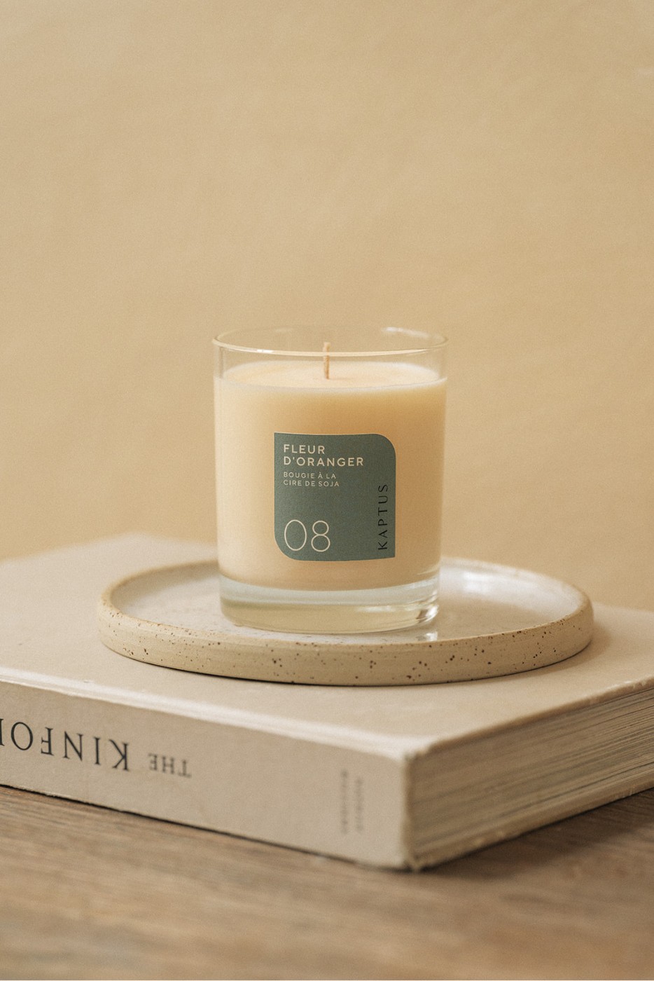 Bougie parfumée à la fleur d oranger, dans un verre transparent, posée sur un plateau en pierre, lui-même sur un livre intitulé